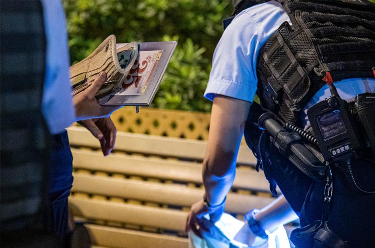 Un agente de policía inspecciona la bolsa de una mujer en el Victoria Park de Hong Kong, donde portaba Mayo 35, una obra sobre la masacre de Tiananmen. 4 de junio de 2024.